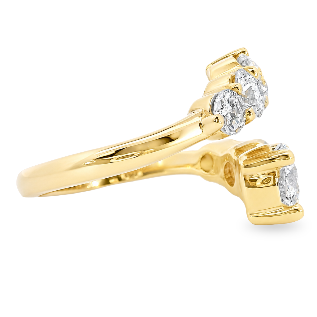 A yellow gold ring with three round-cut diamonds in a three-stone setting, shown from an angled side view on a plain white background.