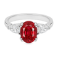 An oval-cut red ruby ring set in a white band with two pear shape clear diamonds on each side, shown against a plain white background.