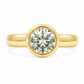 A yellow gold solitaire ring featuring a yellow toned round brilliant-cut diamond in a bezel setting, shown against a clean white background.