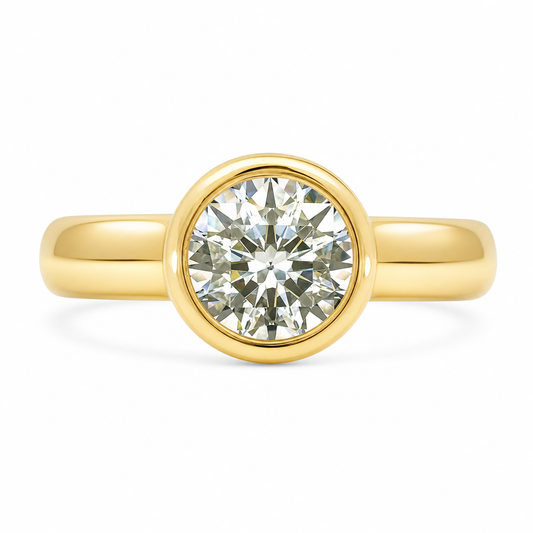 A yellow gold solitaire ring featuring a yellow toned round brilliant-cut diamond in a bezel setting, shown against a clean white background.