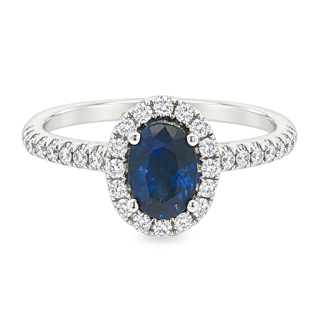 White gold ring with oval blue sapphire surrounded with a halo of diamonds on a diamond band. Shown on a clean white background.