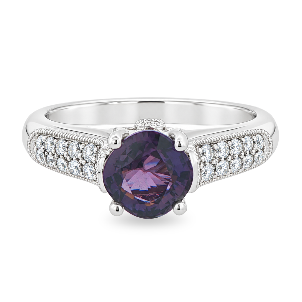 White gold ring with double rows of pave diamonds on the band, set with a purple sapphire. Shown on a clean white background.