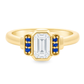 Yellow gold art deco ring with an emerald cut diamond an3 small blue sapphires on either side. Set on a white background.