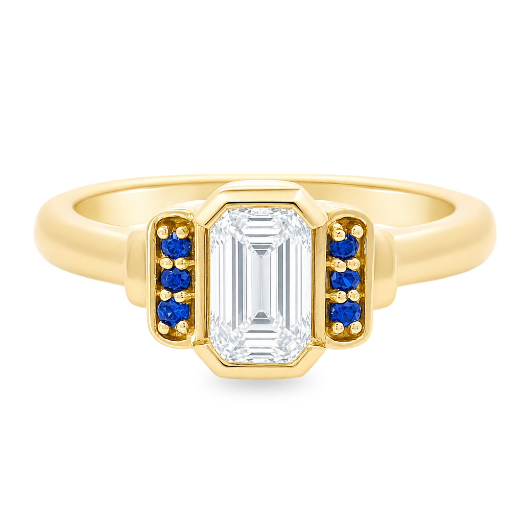 Yellow gold art deco ring with an emerald cut diamond an3 small blue sapphires on either side. Set on a white background.