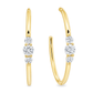 A pair of gold hoop earrings with three round-cut clear gemstones on each earring, displayed against a solid white background.