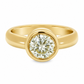 A yellow gold solitaire ring featuring a yellow toned round brilliant-cut diamond in a bezel setting, shown against a clean white background.