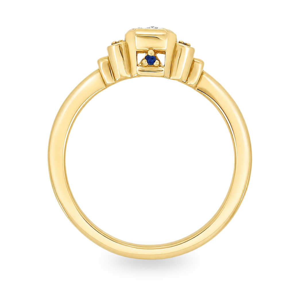 Yellow gold art deco ring with an emerald cut diamond an3 small blue sapphires on either side. Set on a white background.