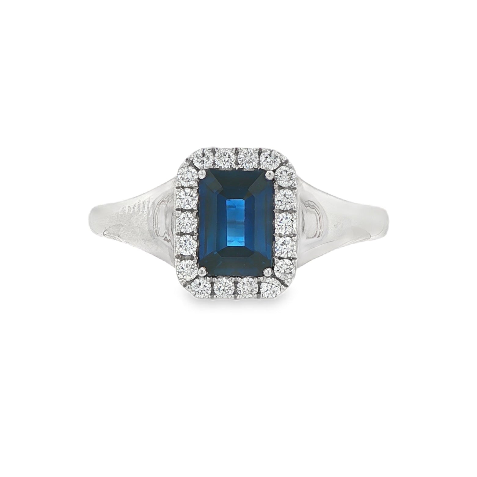 14K White gold ring set with an emerald cut deep blue sapphire surrounded by a halo of round brilliant diamonds. Item J35826 - ABC Jewelry Co. 