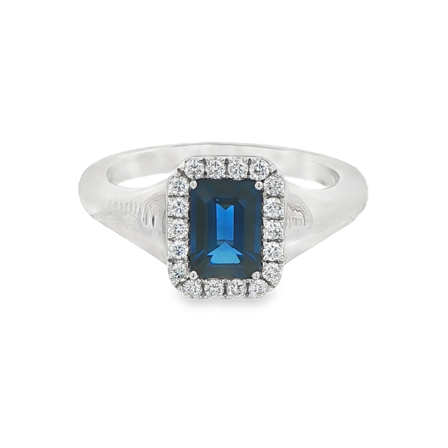 14K White gold ring set with an emerald cut deep blue sapphire surrounded by a halo of round brilliant diamonds. Item J35826 - ABC Jewelry Co. 