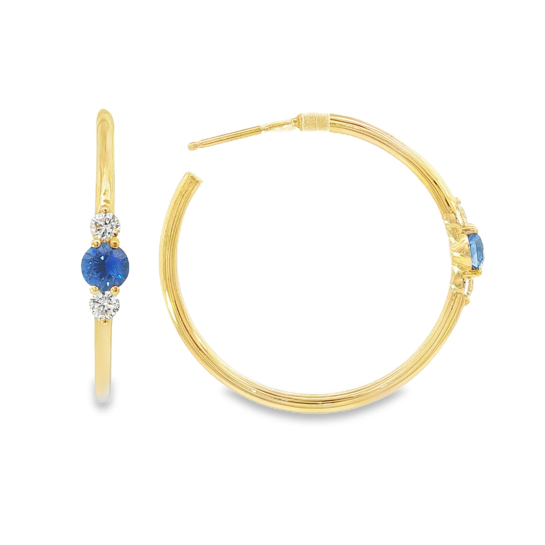 14K Yellow gold hoop earrings, each set with a round blue sapphire flanked by two round diamonds. Item - J39003 - ABC Jewelry Co. 