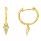 A pair of gold huggie hoop earrings with a dangling chevron design paved with small clear stones, shown on a solid white background.