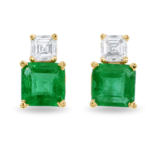 A pair of gold stud earrings featuring a large square-cut emerald gemstone and a smaller square-cut diamond above it, set in yellow gold prong settings on a white background.