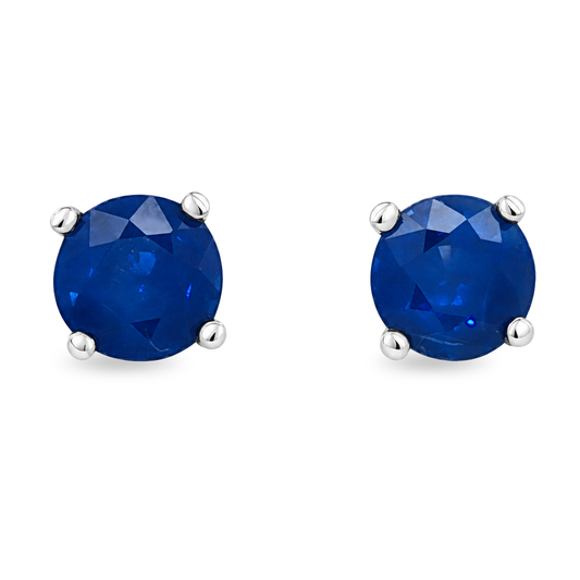 A pair of round-cut blue sapphire stud earrings in a four-prong white gold setting, shown on a plain white background.