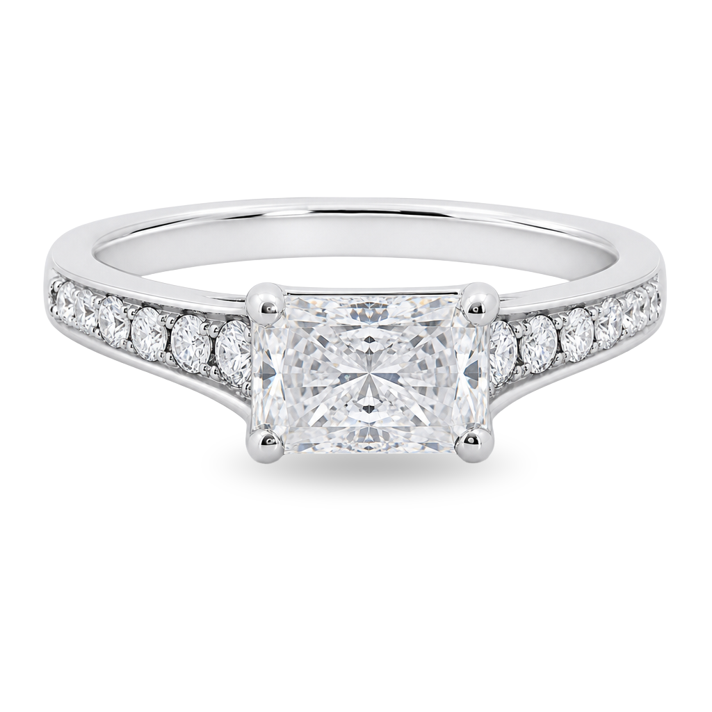 A radiant cut diamond engagement ring in a white gold band with pavé diamonds on either side, shown on a clean white background.