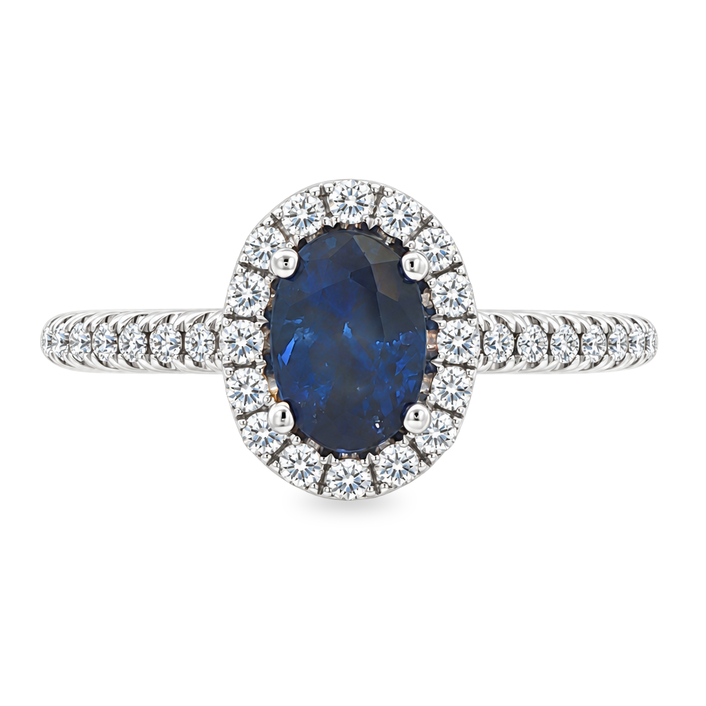White gold ring with oval blue sapphire surrounded with a halo of diamonds on a diamond band. Shown on a clean white background.