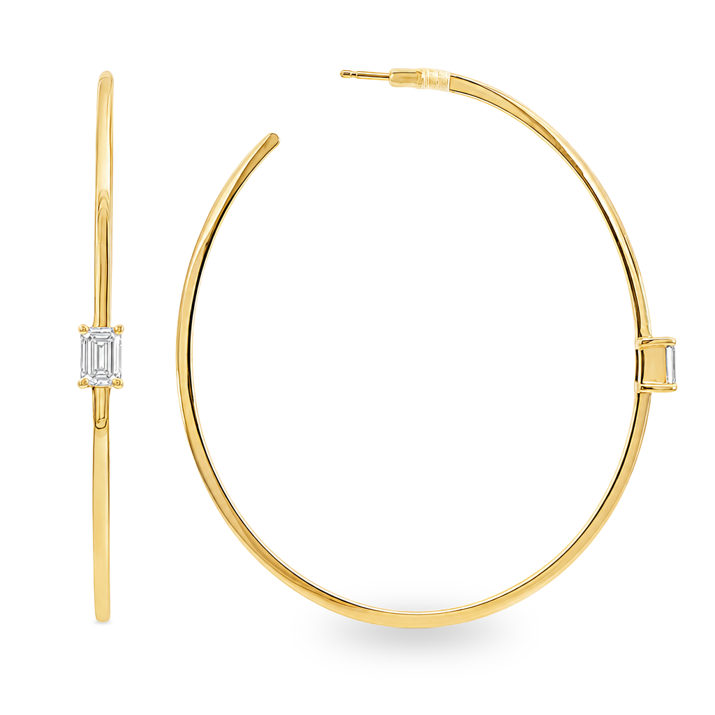 A pair of gold hoop earrings with a single rectangular baguette diamond in a prong setting on each earring, shown against a plain white background.