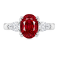 An oval-cut red ruby ring set in a white band with two pear shape clear diamonds on each side, shown against a plain white background.