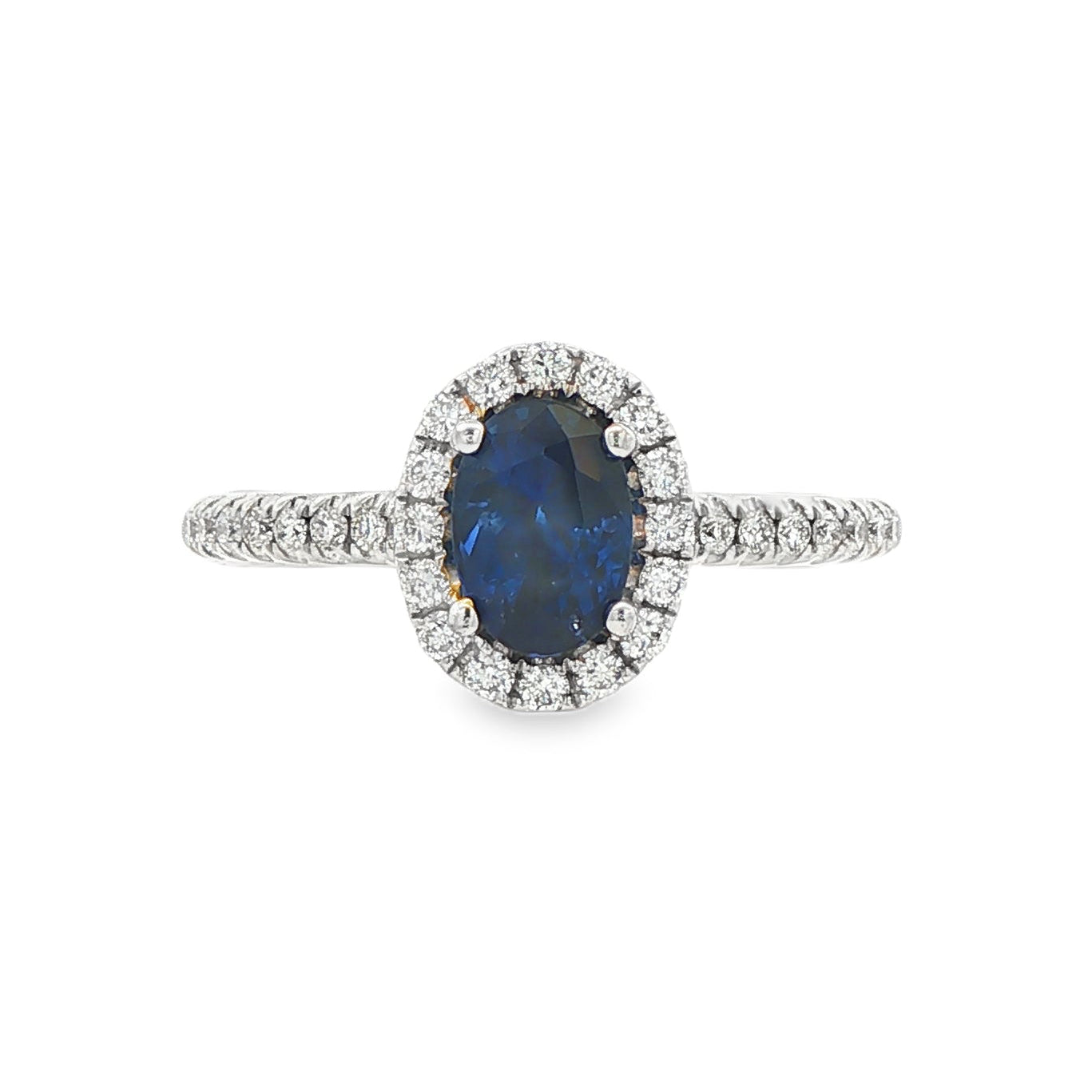 18K White gold ring set with an oval blue sapphire surrounded by a diamond halo. Item J30904 - ABC Jewelry Co. 