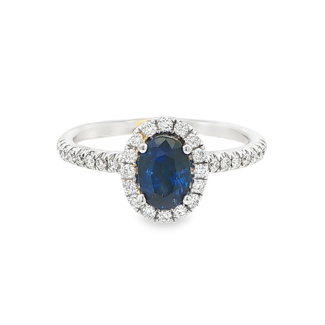 18K White gold ring set with an oval blue sapphire surrounded by a diamond halo. Item J30904 - ABC Jewelry Co. 