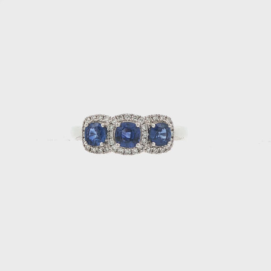 18K White gold ring set with three deep blue sapphires, each surrounded by diamond halo. Item J35620 - ABC Jewelry Co.
