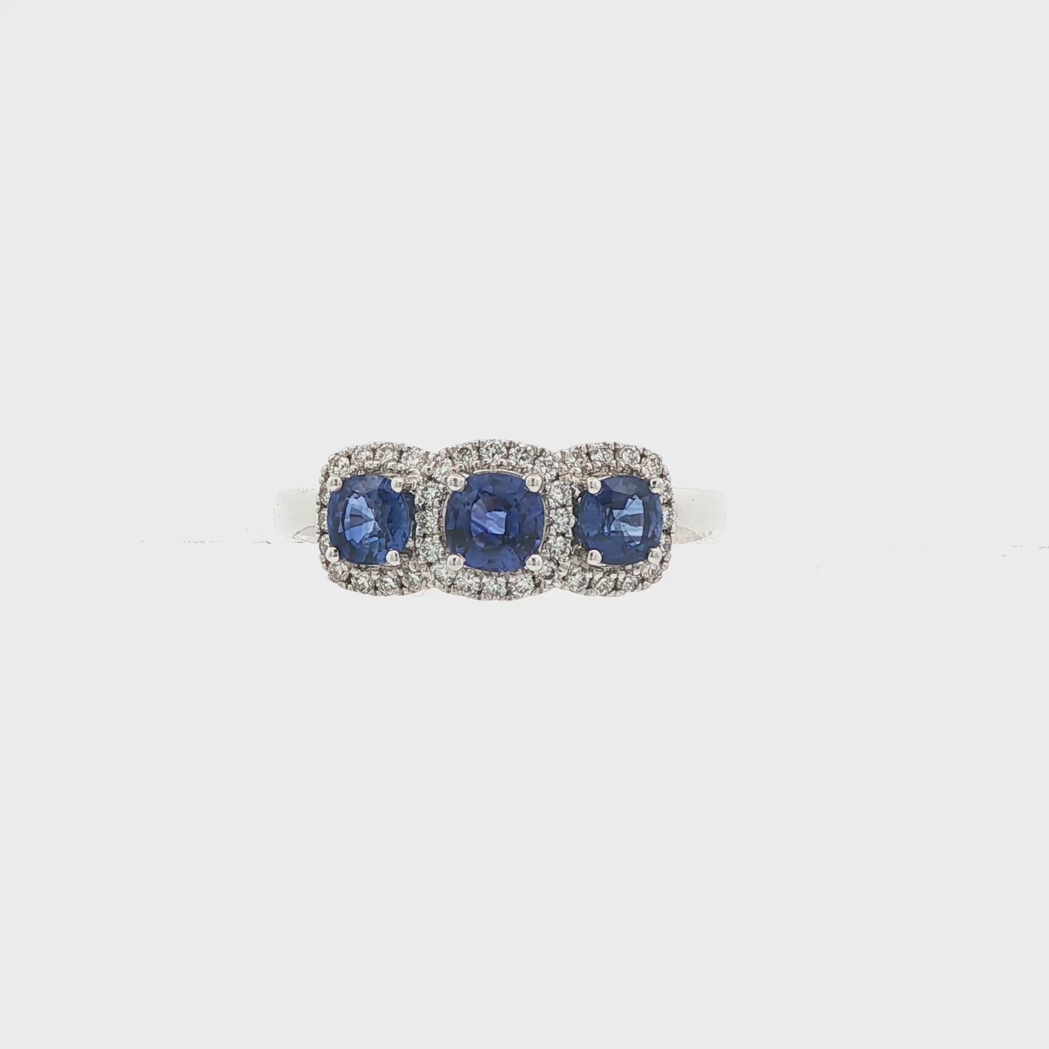 18K White gold ring set with three deep blue sapphires, each surrounded by diamond halo. Item J35620 - ABC Jewelry Co.