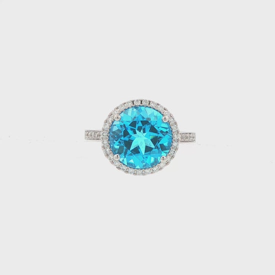 14K White gold ring with a round blue topaz and diamond halo. Item J38755 - ABC Jewelry Co. 