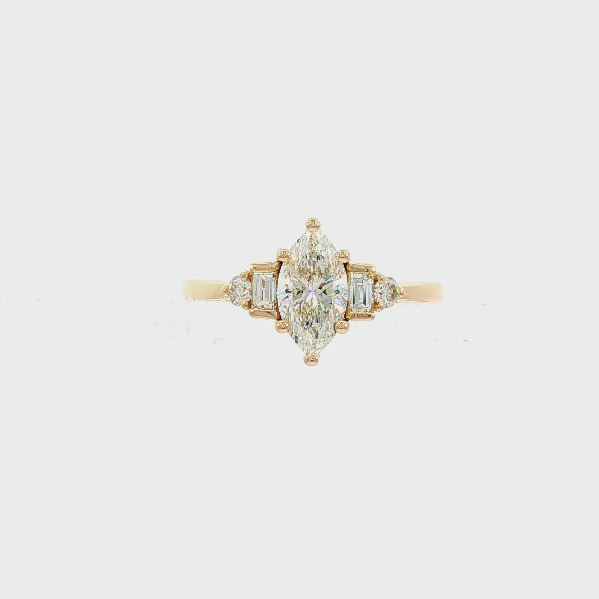 14K Yellow gold ring set with a marquise diamond flanked by baguette and round brilliant diamonds. Item J38803 - ABC Jewelry Co.
