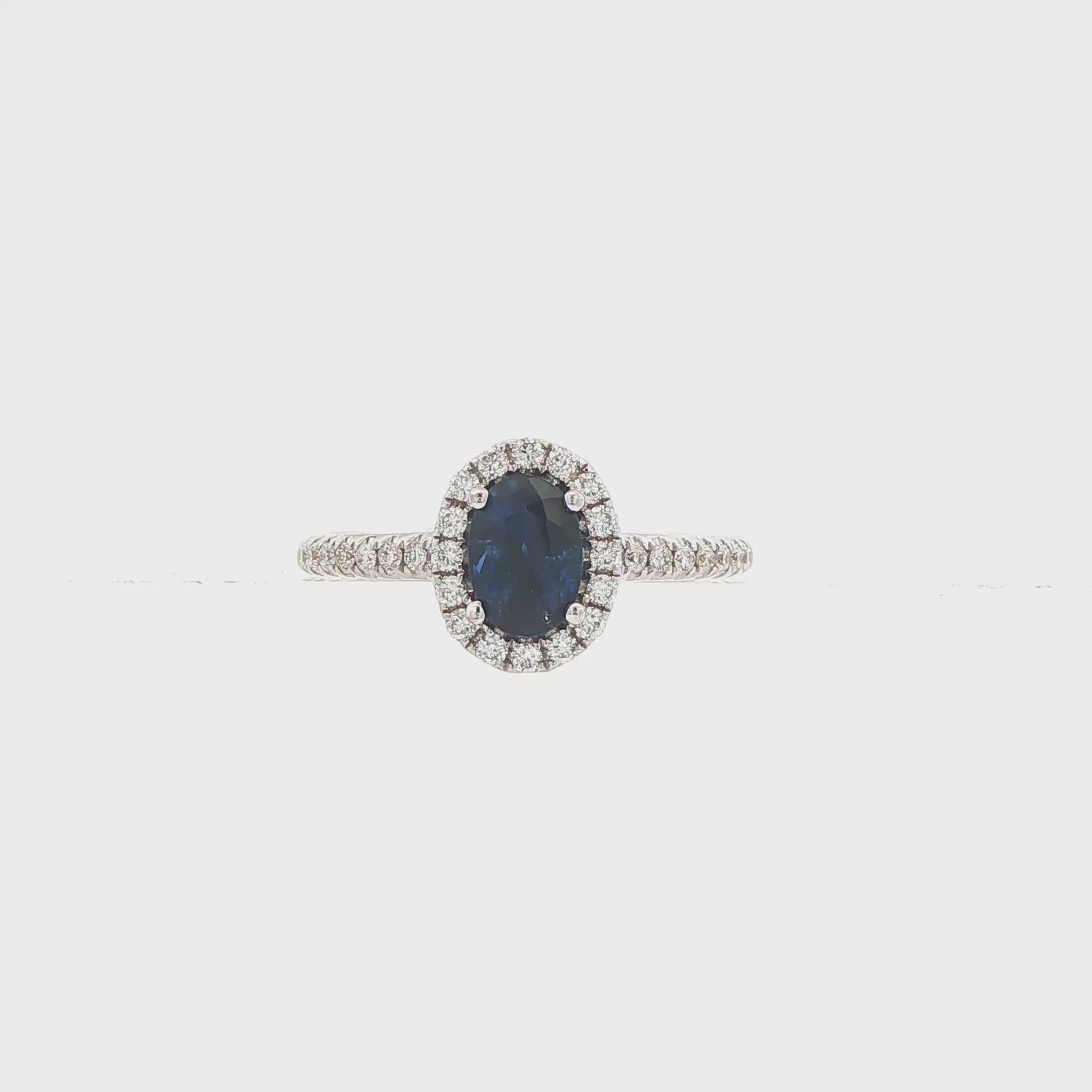 18K White gold ring set with an oval blue sapphire surrounded by a diamond halo. Item J30904 - ABC Jewelry Co. 