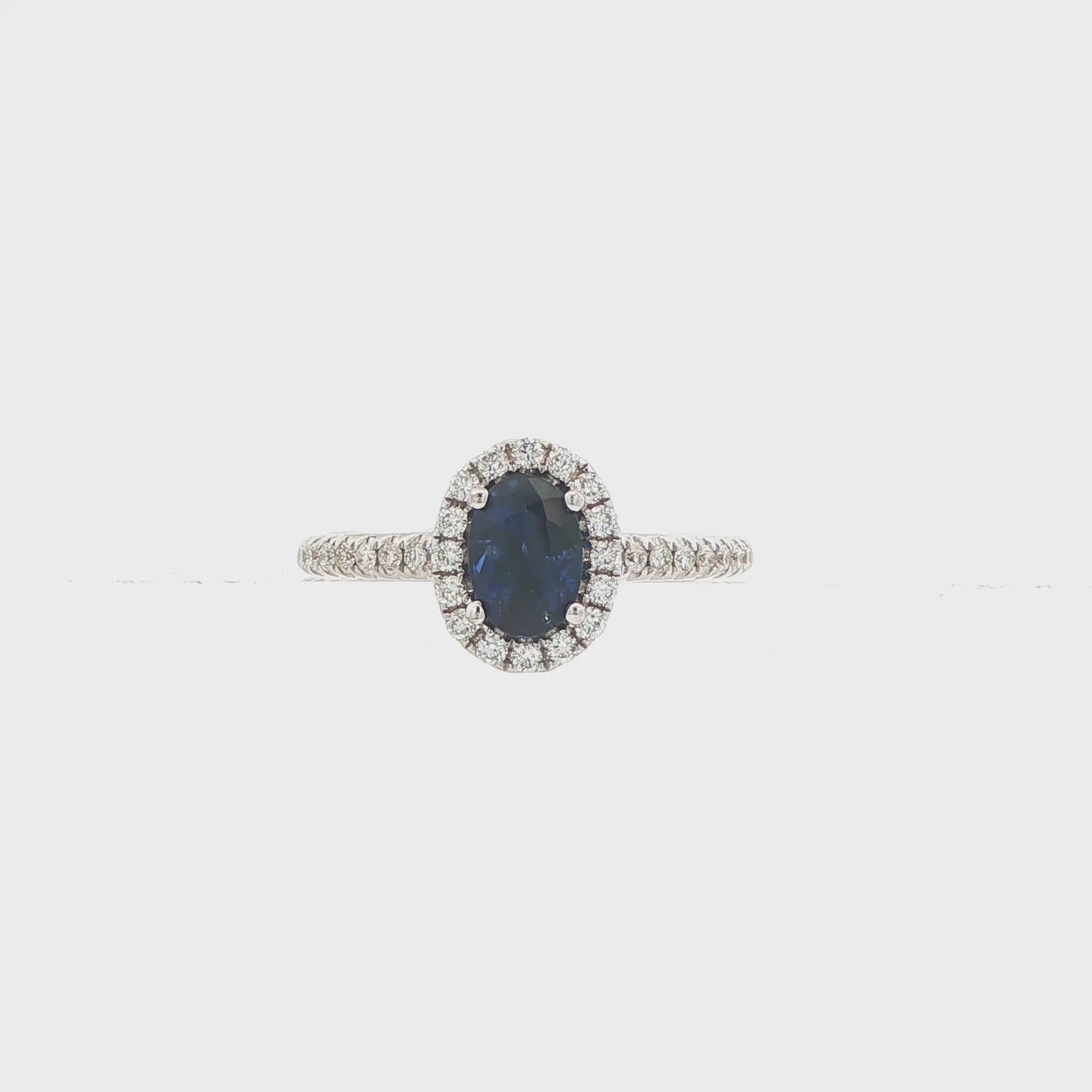 18K White gold ring set with an oval blue sapphire surrounded by a diamond halo. Item J30904 - ABC Jewelry Co. 