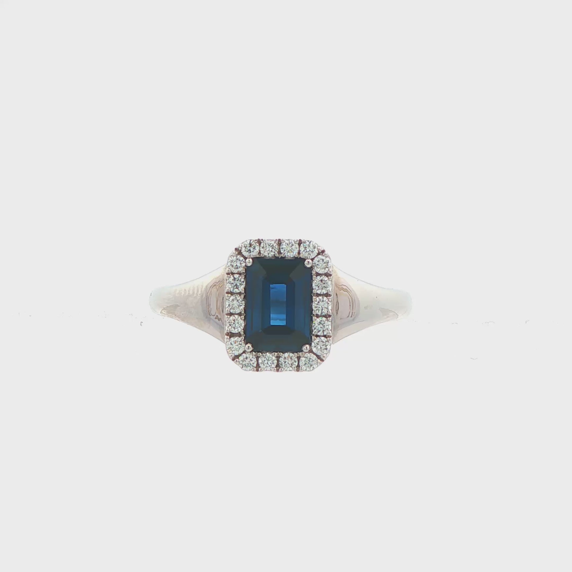 14K White gold ring set with an emerald cut deep blue sapphire surrounded by a halo of round brilliant diamonds. Item J35826 - ABC Jewelry Co. 