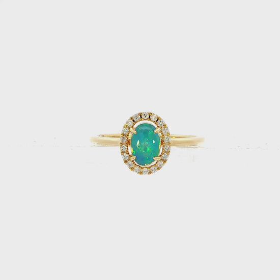 14K Yellow gold ring set with an oval shape opal center stone surrounded by a diamond halo. Item J38784 - ABC Jewelry Co. 